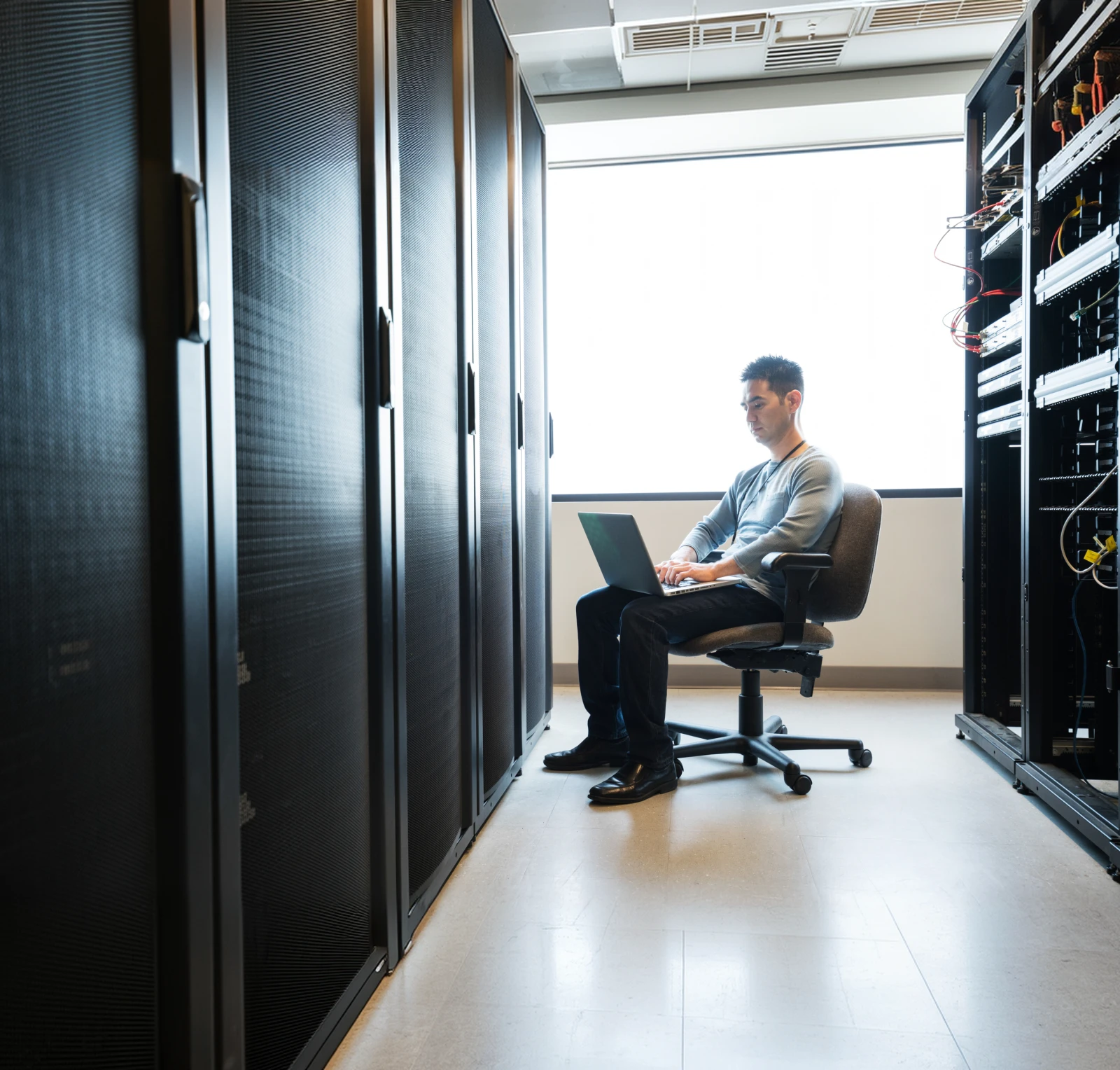 IT-Fachkraft bei der Arbeit zwischen Server-Racks